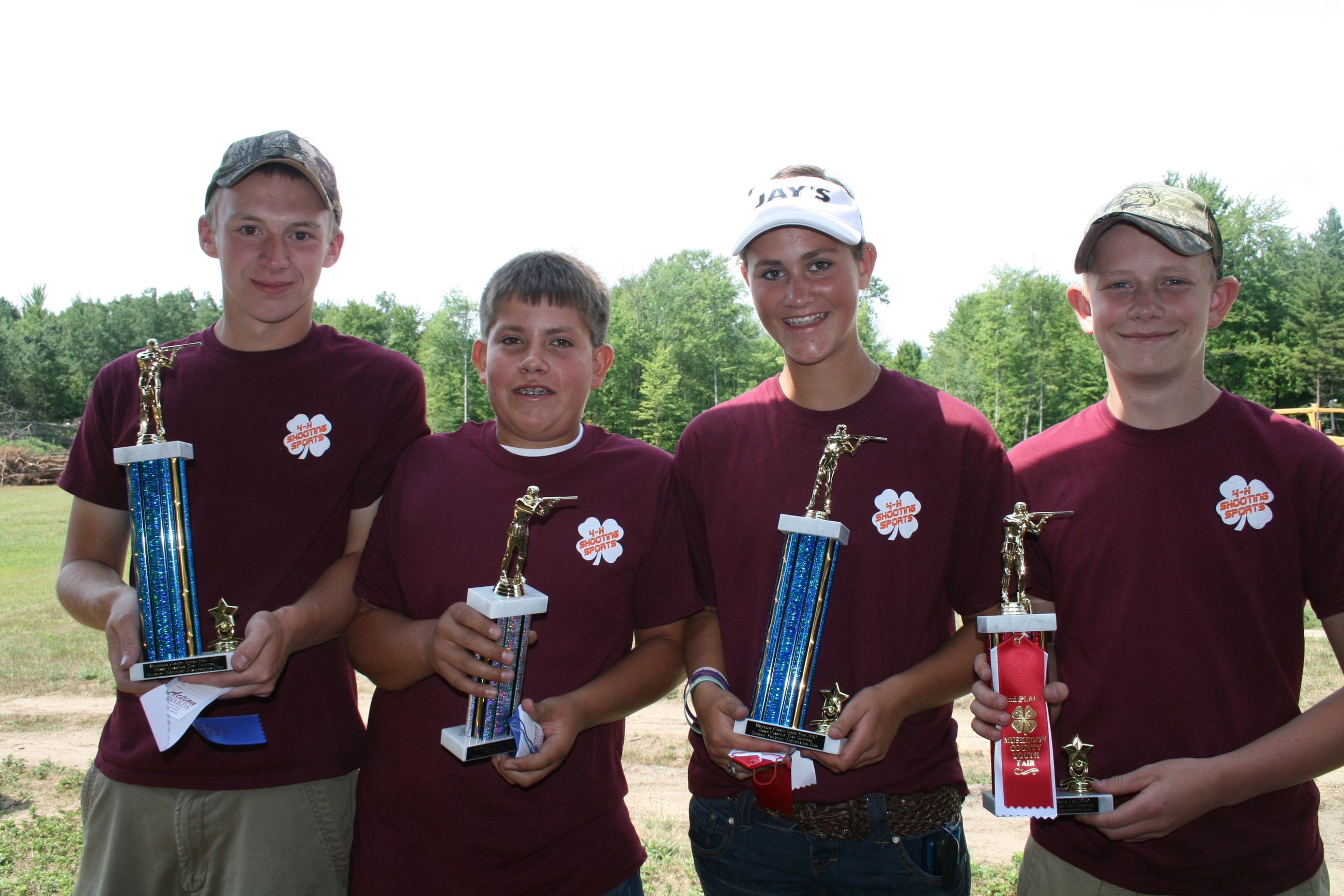 Four youth holding trophies from shooting competition